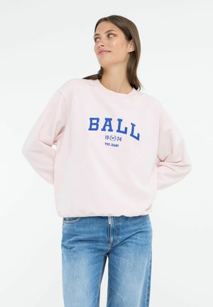Jasnoróżowy sweatshirt z niebieskim napisem "BALL", okrągły dekolt i długie rękawy, w połączeniu z niebieskimi dżinsami. Miękka tkanina i luźny krój.