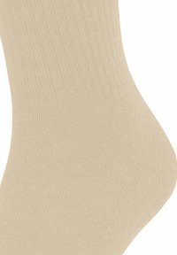 Beige Baumwollsocke mit gerippter Textur, die den Knöchel- und Fersenbereich bedeckt.