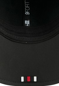 Schwarze Kappe mit runder Form, einem strukturierten Innenraum, einem Logo-Label und einem kleinen farbigen Akzent am Schirm in Rot, Weiß und Schwarz.