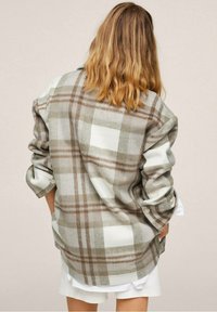 Oversized ruithemd in beige en wit met bruine accenten, voorzien van opgerolde mouwen en een zachte, gestructureerde stof.