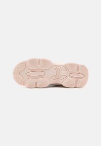 Sole di sneaker in gomma rosa chiaro con motivi di trazione orizzontali e verticali, caratterizzata da un design ovale centrale e un logo al centro.