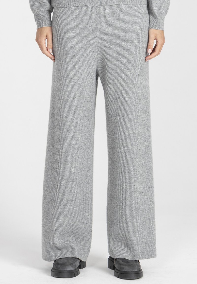 Szerokie spodnie wykonane z miękkiego szarego dzianiny żebrowej, z wysokim stanem i gładką fakturą, w połączeniu z czarnymi płaskimi butami.