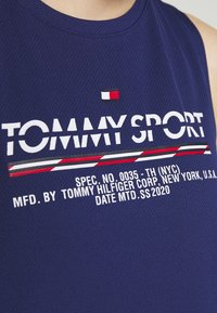 Canotta atletica senza maniche di colore blu navy con texture in rete, con la scritta bianca "TOMMY SPORT" e un piccolo logo con bandiera colorata.