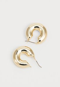 Pendientes de aro en tono dorado con un diseño curvado, que cuentan con un acabado brillante y una pequeña abertura. Están fabricados en metal y tienen un gancho de alambre para el cierre.