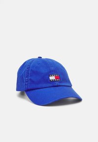 Spilgti zils kokvilnas beisbola cepure ar noapaļotu vizieri, kurai ir taisnstūrveida logo plāksne sarkanā, baltā un melnā krāsā ar uzrakstu "TOMMY JEANS".