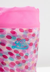 Sac transparent avec un haut rose vif ; présente un motif de pois multicolores en rose, bleu et violet ; logo turquoise près de la base.