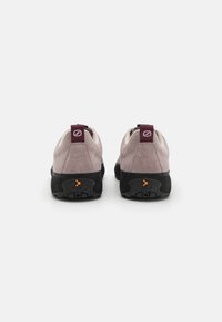 Suedesko i lyserosa med en svart gummisula. Har forsterket hæl, kontrastfargede maroon-detaljer og oransje detaljer på sålen.