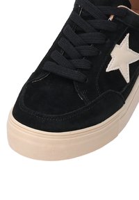 Schwarze Wildledersneaker mit einem cremefarbenen Sternakzent, flachen schwarzen Schnürsenkeln und einer strukturierten beigen Gummisohle. Verfügt über gebogene Nähte entlang der Kanten.