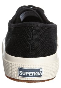 Sneaker nera in tela con superficie testurizzata, suola in gomma bianca e etichetta "SUPERGA" sul retro. Design classico a profilo basso.