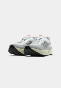 Light gray athletic shoes with a breathable upper, a textured black rubber outsole, and subtle lime green accents on the sole edge.