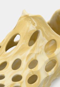 Κίτρινο παπούτσι χωρίς κορδόνια με μαρμάρινο σχέδιο, κατασκευασμένο από ευλύγιστο υλικό με πολλαπλές οβάλ οπές για αερισμό και ομαλή υφή.