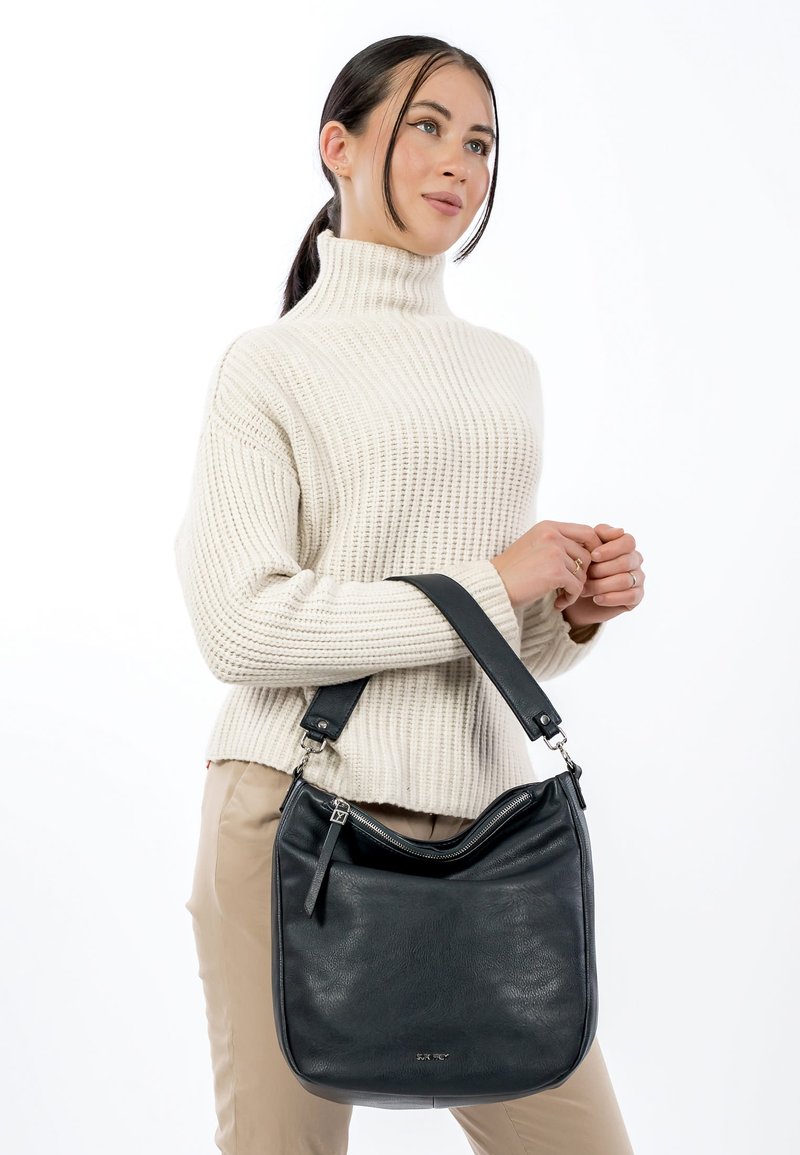 Musta nahkainen olkalaukku, jossa on kaareva yläosa ja säädettävä hihna, vetoketjullinen suljin ja minimalistinen muotoilu. Sileä pinta.