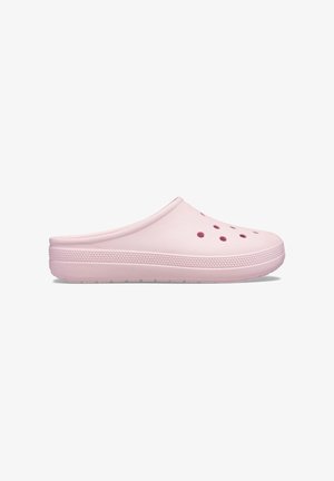 Zueco rosa claro sin cordones con orificios de ventilación cerca de la punta y suela texturizada, mostrado de perfil sobre un fondo blanco.