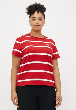 Piros csíkos póló, fehér vízszintes csíkokkal, rövid ujjakkal és kerek nyakkivágással; bal melle részen egy kis logó található.