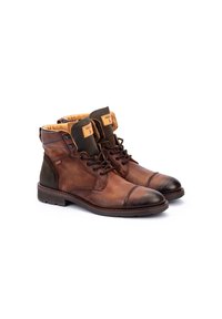 Botas de cuero marrón hasta el tobillo con un acabado liso, secciones verdes contrastantes, puntera redonda y cuello acolchado. Cuenta con cordones y etiquetas de marca.