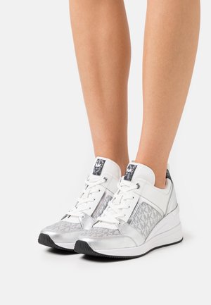Sneakers bianchi e argento che presentano un mix di materiali, tra cui pelle lucida e dettagli testurizzati, con tacco a zeppa e dettagli con logo.
