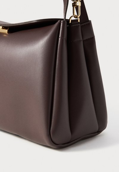 Brown faux leather handbag with a structured design, featuring a smooth texture, gold-toned hardware, and pleated sides.