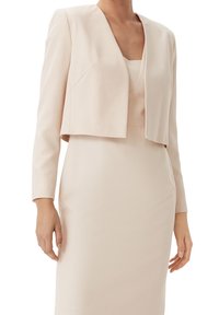 Ljusrosa kort jacka med långa ärmar, slät tyg och V-ringning, kombinerad med en figursydd klänning i matchande ton.