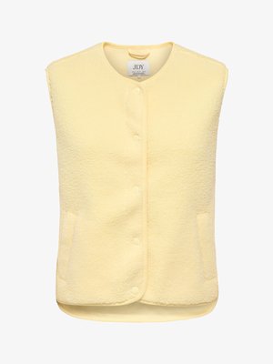 Kollane fliisvest ümmarguse kaelusega, ees käepaelade ja kahe küljetaskuga. Pehme tekstuuriga, hubase välimusega ja varrukateta.