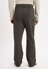 Olive green sweatpants with a relaxed fit, elastic waistband, side pockets, and visible stitching details, shown from the back.