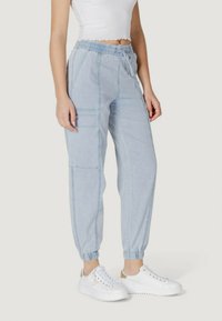 Pantaloni cargo de culoare albastru deschis cu talie elastică, șnur și tivuri cu manșete. Prezintă multiple buzunare și un design texturat al materialului.