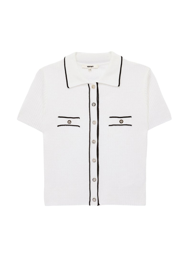 Polo shirt bianco a maniche corte con bordi neri, due taschini frontali piccoli con contorno nero e bottoni argentati sulla parte anteriore.