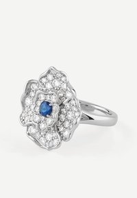 Srebrny pierścionek w kształcie kwiatu z centralnym niebieskim kamieniem, otoczonym przez grupę mniejszych przezroczystych kamieni, z misternym wzorem płatków.
