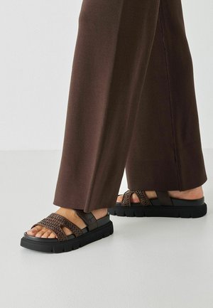 Brown sandals with woven accents, durable black rubber soles, and adjustable straps, featuring an open-toe design and textured detailing.