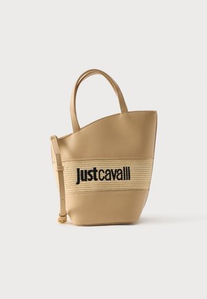 Béžová kabelka ve tvaru kbelíku se středovým panelem z tkaniny a černým nápisem „just cavalli“, vybavená dvěma úchyty a nastavitelným ramenním popruhem.