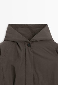 Giacca a cappuccio marrone scuro con chiusura frontale a bottoni e dettagli di cucitura visibili, esposta su uno sfondo bianco.