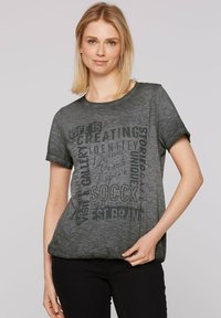 Szara bawełniana koszulka z krótkim rękawem, z nadrukowanym tekstem w ciemniejszym odcieniu szarości oraz metalicznymi akcentami na przodzie.