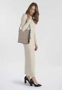 Borsa a tracolla in pelle grigia chiara, con una finitura liscia, accenti verdi, tracolla regolabile e design minimalista.