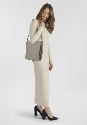 Sac en toile en cuir gris clair, avec une finition lisse, des accents verts, une bandoulière ajustable et un design minimaliste.