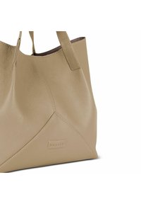 Beige leren schoudertas met een gestructureerde afwerking, met een driehoekig ontwerp en platte handvatten. Merklabel zichtbaar aan de voorkant.