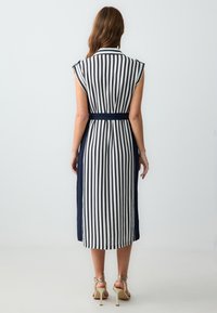 Gestreiftes Hemdblusenkleid mit vertikalen Marineblau- und Weißstreifen, kurzen Ärmelchen, einem taillierten Gürtel und einer Länge bis zur Wade. Glatte Stofftextur.