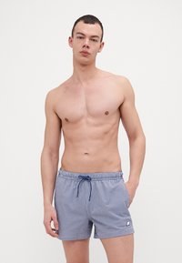 Sini ja valge ruuduline ujumispüksid elastse vöökoha, nööri ja väikese logoga vasakul äärtes. Sile kangas.