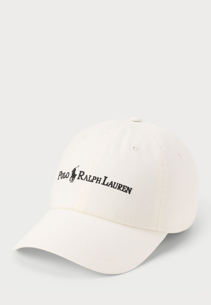 Biely bavlnený baseballový klobúk s oblúkovým okrajom, ktorý ma vyšívané logo "Polo Ralph Lauren" v čiernej farbe na prednej strane.