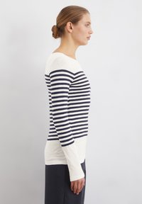 Long-sleeve top featuring navy and white horizontal stripes, made from soft material with a round neckline and fitted design.