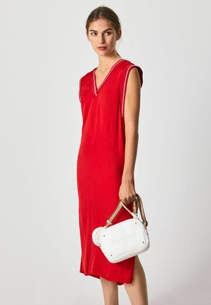 Vestido rojo de longitud a la rodilla con escote en V y mangas cortas; textura suave. Bolsa blanca con estrellas doradas y logotipo, con dos asas.