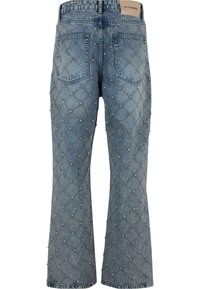 Niebieskie dżinsy z rozkloszowanymi nogawkami, pikowany wzór, rozmieszczone małe srebrne ćwieki, tylne kieszenie oraz beżowa skórzana metka marki w talii.