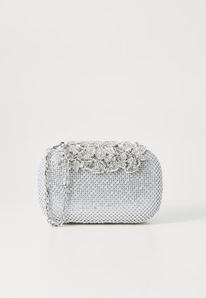 Clutch plateado adornado con cristales, con cierre floral de metal y una cadena delgada sobre un fondo blanco liso.