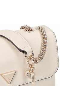 Bolso de mano de cuero crema con un diseño estructurado, correa de cadena plateada y acentos con el logo. Presenta un cierre de solapa y herrajes pulidos.