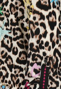 Leopardenmusterstoff mit beige, braunen und schwarzen Tönen, akzentuiert durch bunte Blumendetails. Verfügt über einen Knopf und dekorative Steppnähte.