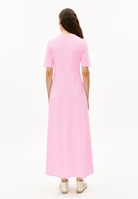 Pink maxi dress with short sleeves, featuring a fitted bodice and a loose, flowing skirt. Material appears smooth and lightweight.