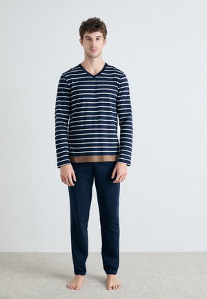 Gestreiftes langärmliges V-Ausschnitt-Oberteil in Marineblau und Beige mit einem einfarbigen beigen Band; kombiniert mit einfarbigen marineblauen Hosen, beide aus weichem Stoff.