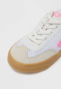 Λευκό αθλητικό παπούτσι με διχτυωτό ύφασμα, λεπτομέρειες από ανοιχτό γκρι σουέντ, υφή στη σόλα από καουτσούκ και ροζ λογότυπο. Διαθέτει επίπεδα κορδόνια και ενισχυμένες ραφές.