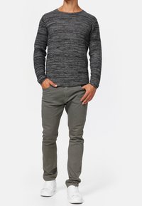 T-shirt à manches longues gris avec un motif rayé texturé, associé à un pantalon slim gris clair et des baskets blanches.