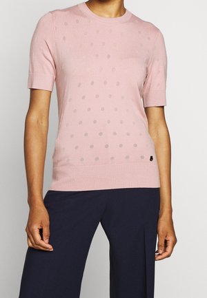 Světlounce růžový krátký svetr s malým puntíkovaným vzorem, žebrovaným výstřihem a lemem, nošený s tmavě námořnickými širokými kalhotami.