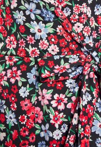 Květinová textilie s malými červenými, růžovými a modrými květy na černém pozadí. Látka je lehká s jemnou strukturou, doplněná zelenými listy.