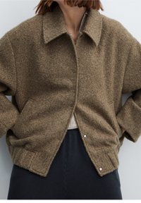 Brown textured wool jacket with a collared neckline, snap closure, and side pockets. Features a relaxed fit and soft finish.